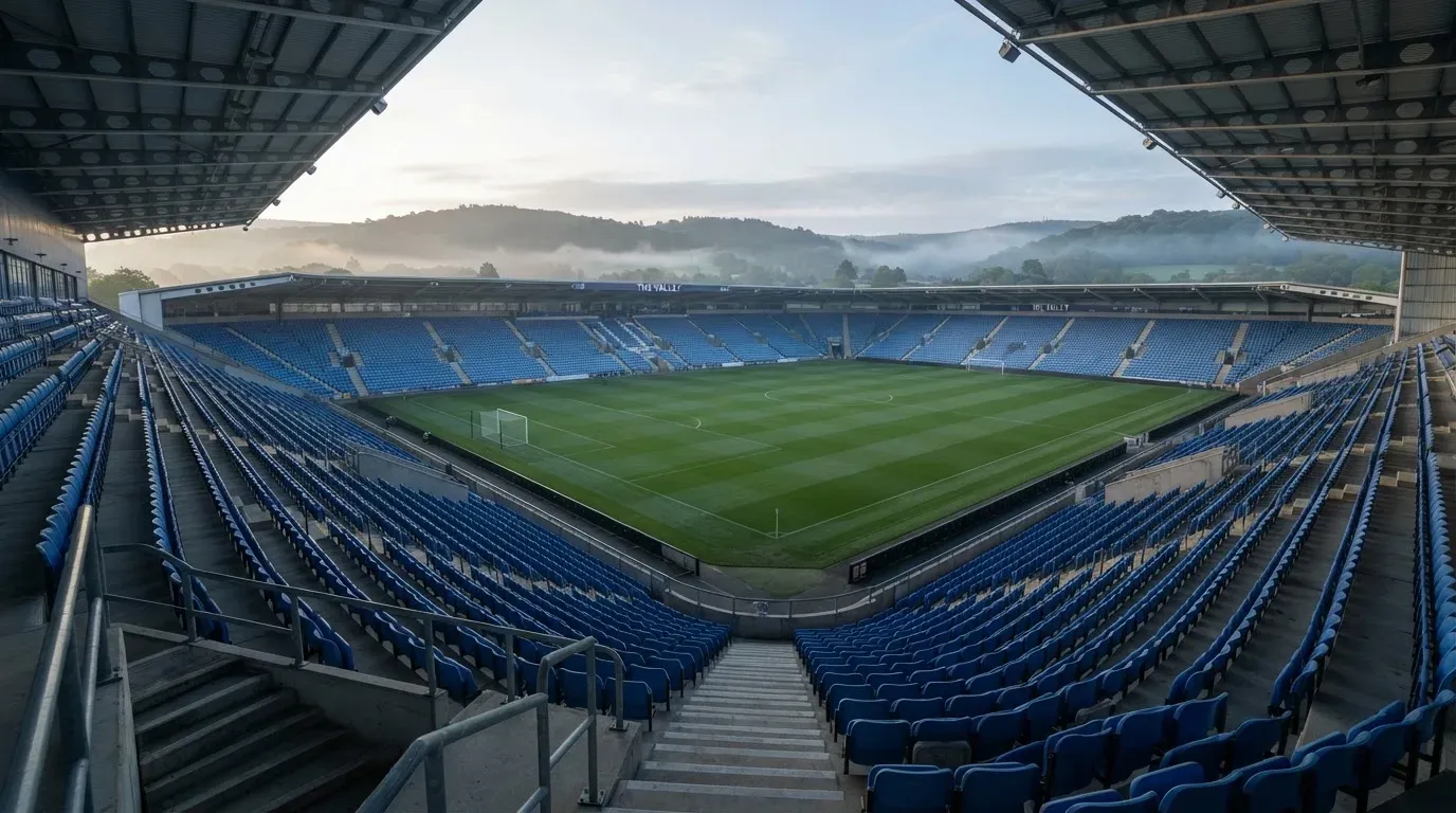 Ein leeres Stadion im Morgenlicht mit Blick auf die Sitzreihen, im Hintergrund Hügel und aufsteigender Nebel.