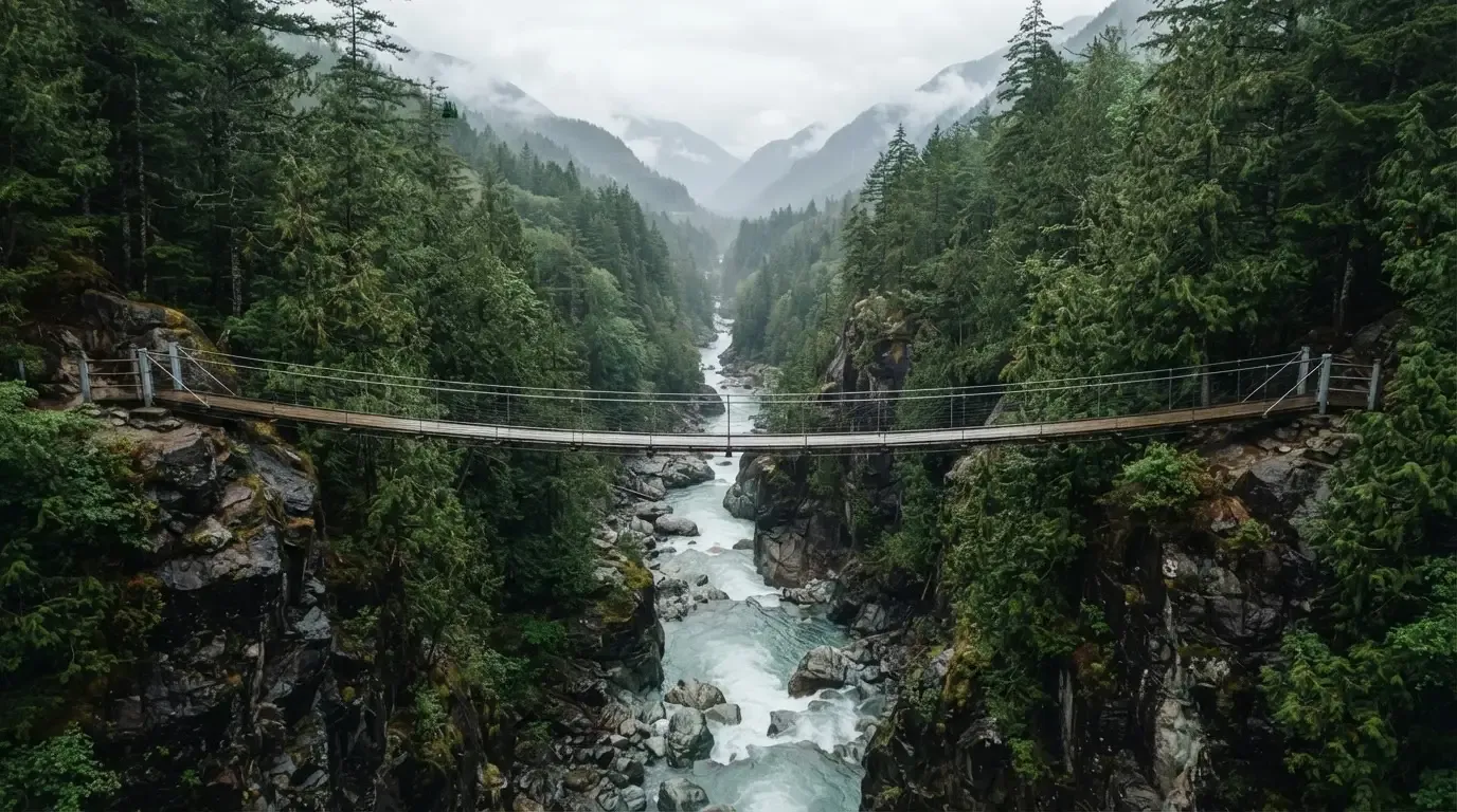 Eine Hängebrücke spannt sich über eine tiefe Schlucht, unten rauscht ein Fluss zwischen bewaldeten Felswänden.