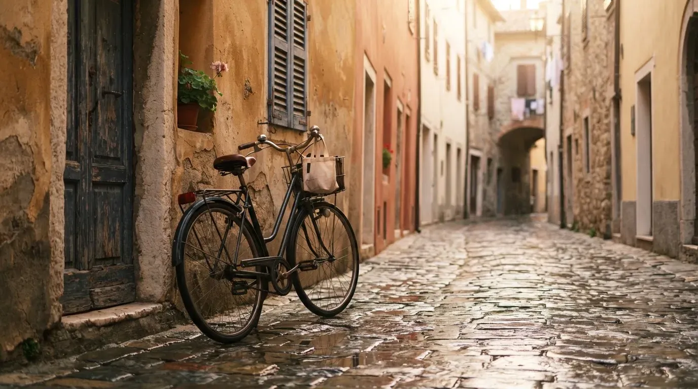 Ein Fahrrad lehnt an einer Mauer in einer Altstadtgasse, das Kopfsteinpflaster glänzt nass nach dem Regen.