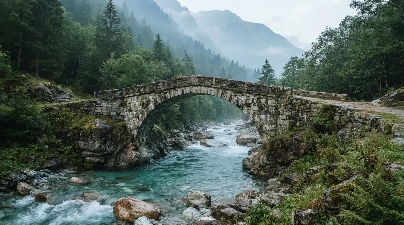 Eine alte Steinbrücke überspannt einen Gebirgsfluss, im Hintergrund steigen bewaldete Hänge an.