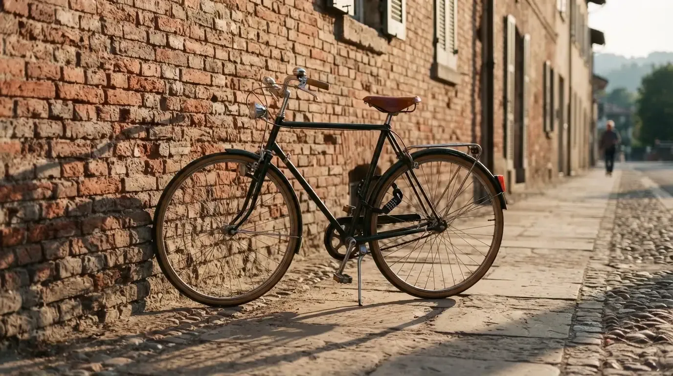 Ein Fahrrad lehnt an einer Backsteinmauer, auf dem Gehweg davor fallen lange Schatten.